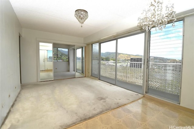 unfurnished sunroom featuring a chandelier and a mountain view