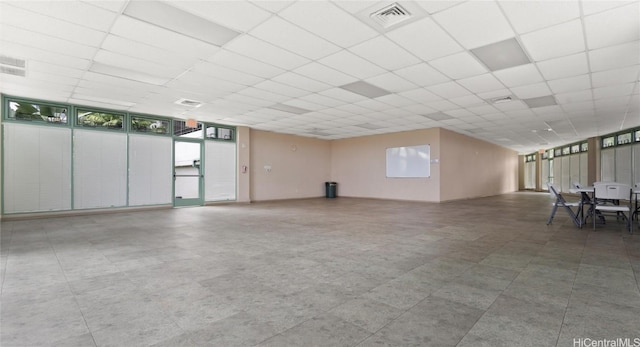 empty room featuring floor to ceiling windows and a paneled ceiling