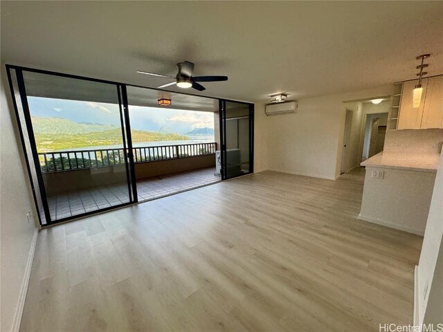 unfurnished living room featuring ceiling fan, light hardwood / wood-style flooring, and an AC wall unit