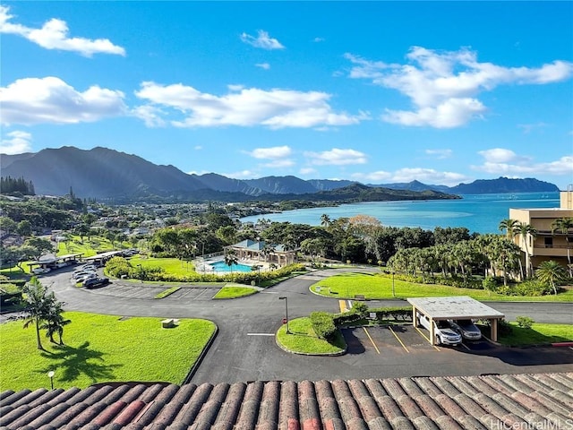 surrounding community featuring a water and mountain view and a lawn