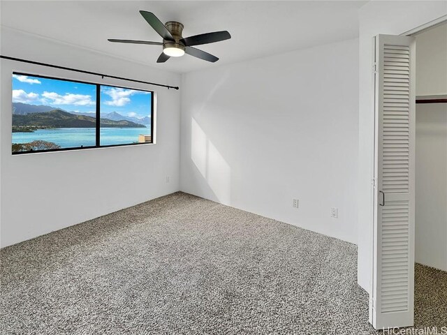 unfurnished bedroom featuring carpet floors, ceiling fan, and a closet