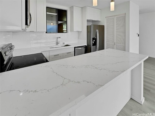 kitchen featuring appliances with stainless steel finishes, light stone countertops, sink, and white cabinets