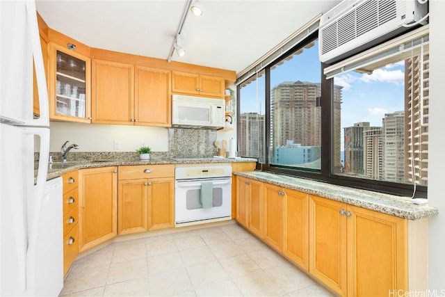 kitchen with an AC wall unit, white appliances, decorative backsplash, sink, and light stone counters