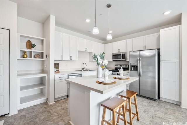 kitchen featuring a breakfast bar, sink, white cabinetry, hanging light fixtures, and appliances with stainless steel finishes