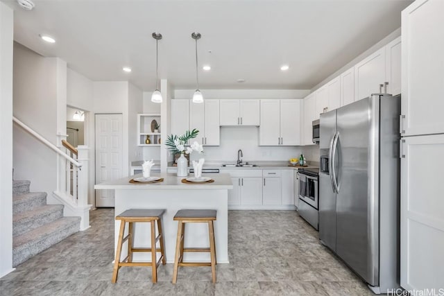 kitchen featuring a breakfast bar, sink, white cabinetry, a kitchen island, and stainless steel appliances