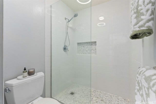 bathroom featuring tiled shower and toilet