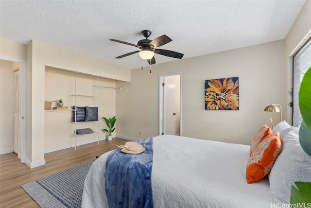 bedroom with ceiling fan, wood-type flooring, a closet, and a textured ceiling