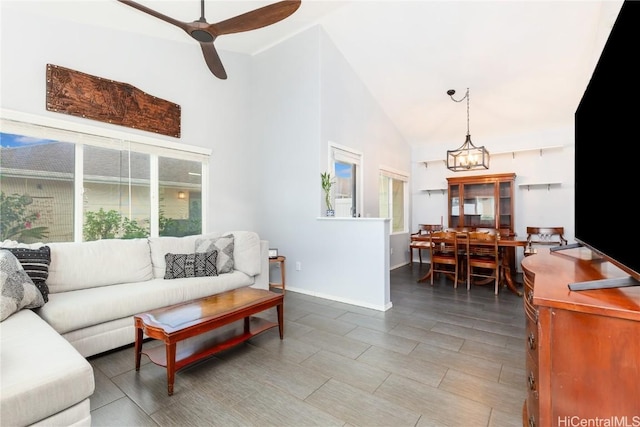 living room with a wealth of natural light, ceiling fan with notable chandelier, and high vaulted ceiling