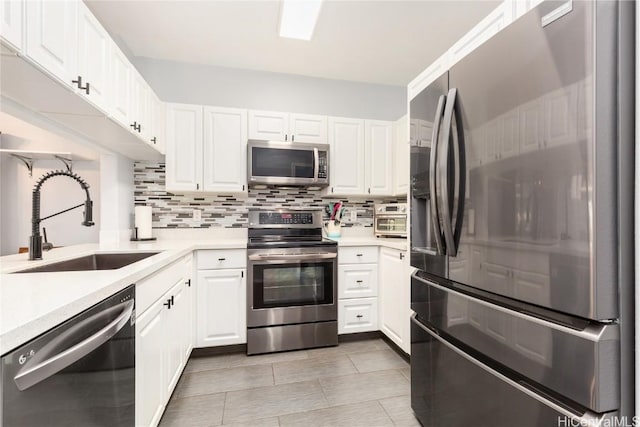 kitchen with tasteful backsplash, sink, white cabinetry, appliances with stainless steel finishes, and light tile patterned floors