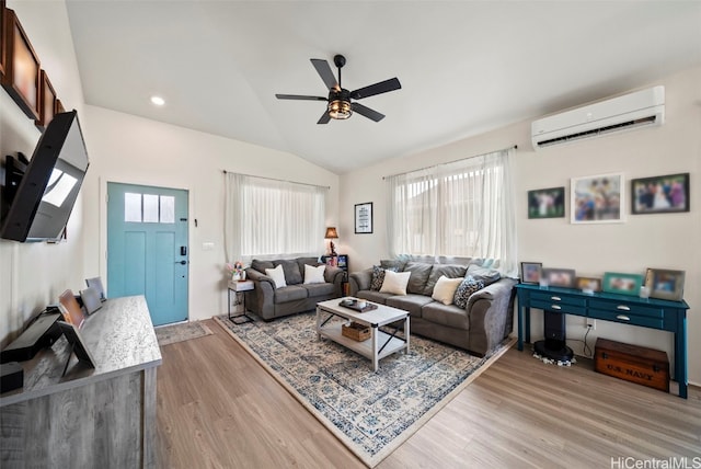 living room featuring lofted ceiling, an AC wall unit, ceiling fan, and light wood-type flooring