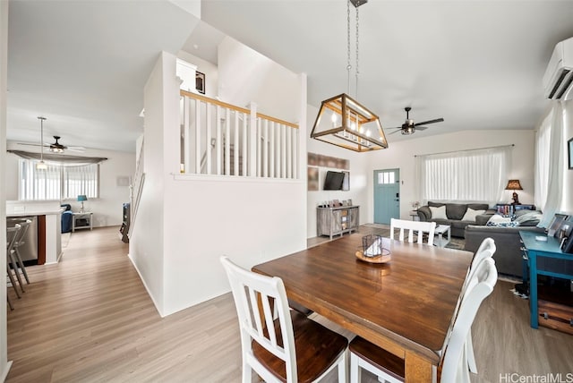 dining area featuring vaulted ceiling, ceiling fan, light hardwood / wood-style floors, and a wall unit AC