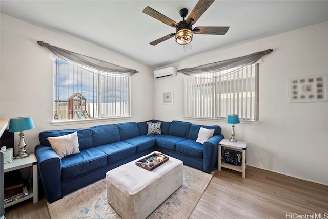 living room featuring ceiling fan, a wall mounted air conditioner, hardwood / wood-style floors, and a wealth of natural light