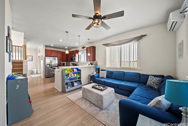 living room featuring a wall mounted air conditioner, light hardwood / wood-style flooring, and ceiling fan