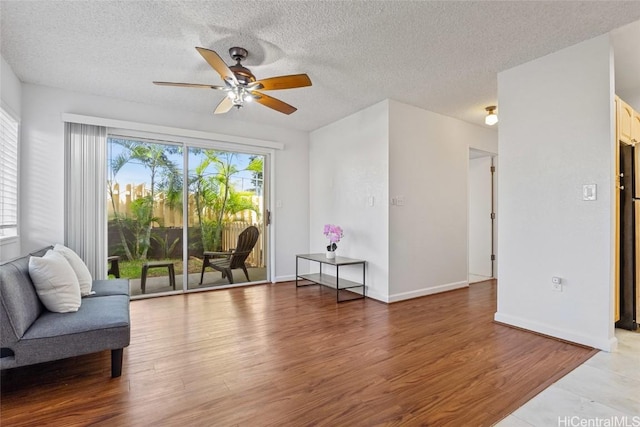 living area with wood-type flooring, ceiling fan, and a textured ceiling