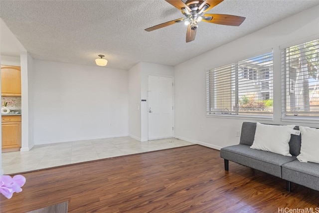 sitting room featuring ceiling fan, light hardwood / wood-style flooring, and a textured ceiling