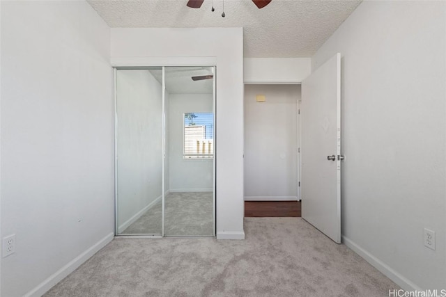 unfurnished bedroom featuring ceiling fan, light carpet, a closet, and a textured ceiling