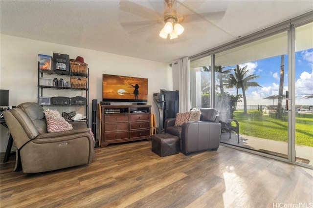 living room with hardwood / wood-style flooring, ceiling fan, expansive windows, and a textured ceiling