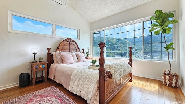 bedroom with wood-type flooring, a textured ceiling, and vaulted ceiling