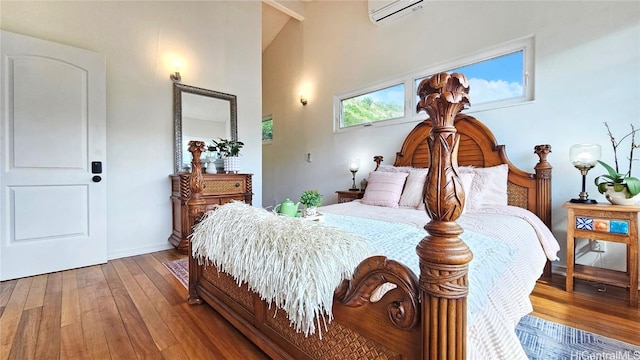 bedroom featuring hardwood / wood-style flooring, a wall mounted AC, and high vaulted ceiling