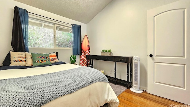 bedroom featuring lofted ceiling, a textured ceiling, and light wood-type flooring