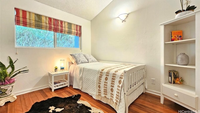 bedroom featuring vaulted ceiling, a textured ceiling, and wood-type flooring