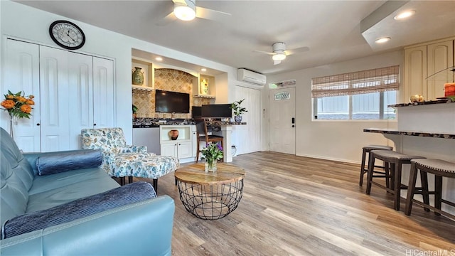 living room with ceiling fan, light hardwood / wood-style floors, and a wall unit AC