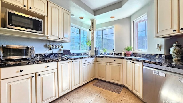 kitchen featuring light tile patterned floors, appliances with stainless steel finishes, sink, and dark stone countertops