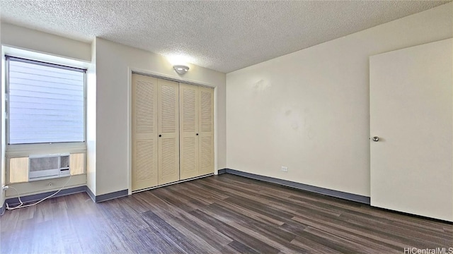 unfurnished bedroom with a closet, cooling unit, dark hardwood / wood-style floors, and a textured ceiling