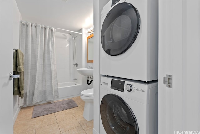 washroom featuring light tile patterned flooring, stacked washing maching and dryer, and sink