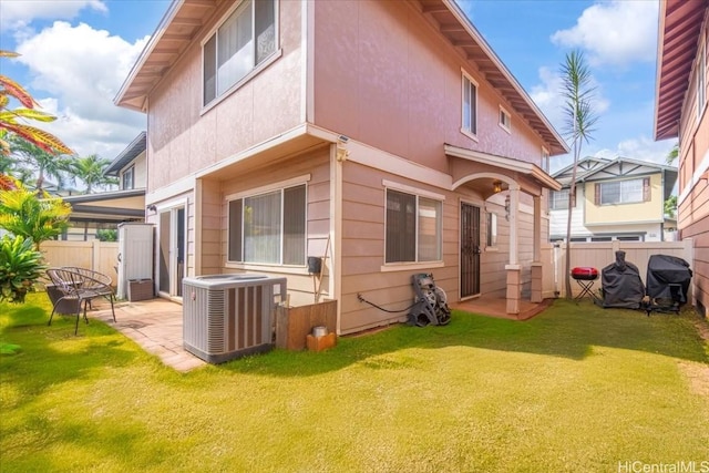 back of property with a patio area, a lawn, and central AC