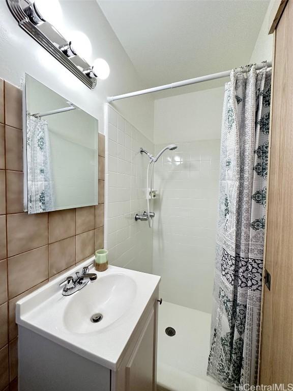 bathroom with tile walls, a shower with curtain, tasteful backsplash, and vanity