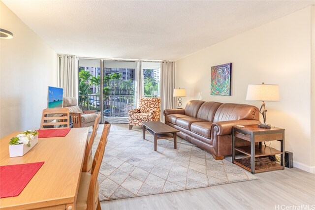 living room featuring hardwood / wood-style flooring, a textured ceiling, and a wall of windows