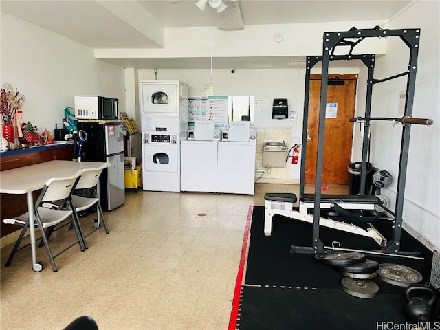 exercise room with light floors, a ceiling fan, and stacked washer / dryer