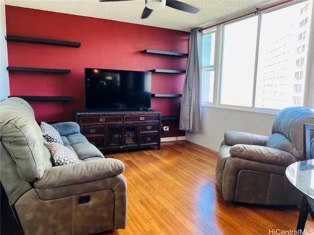 living area with a ceiling fan, a textured ceiling, and light wood finished floors