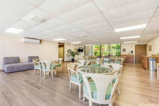 dining area featuring expansive windows, light wood-type flooring, a drop ceiling, and a wall unit AC