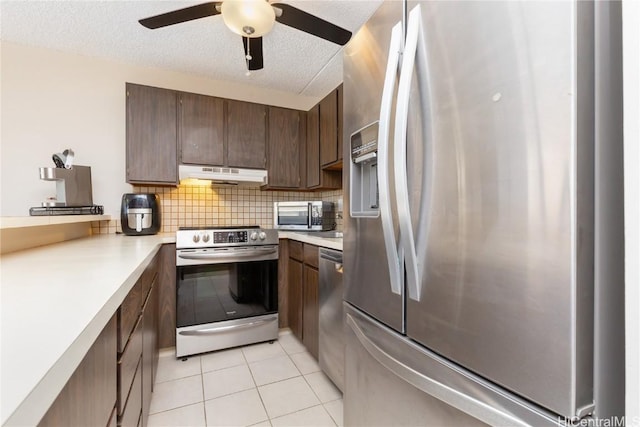 kitchen with ceiling fan, a textured ceiling, stainless steel appliances, and light tile patterned flooring