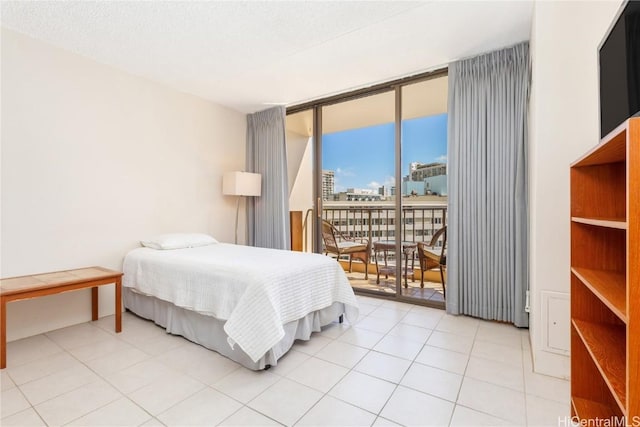 bedroom with a textured ceiling, light tile patterned floors, access to exterior, and floor to ceiling windows