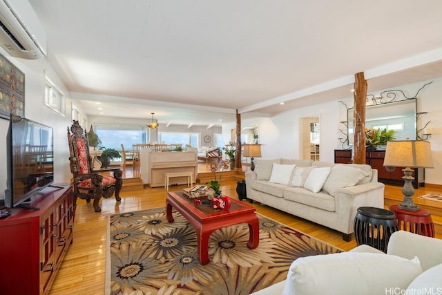 living room featuring an AC wall unit, an inviting chandelier, and light hardwood / wood-style flooring