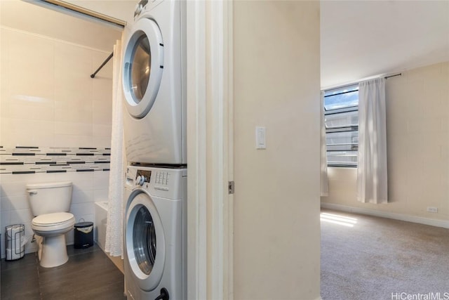 clothes washing area with stacked washer / dryer and tile walls