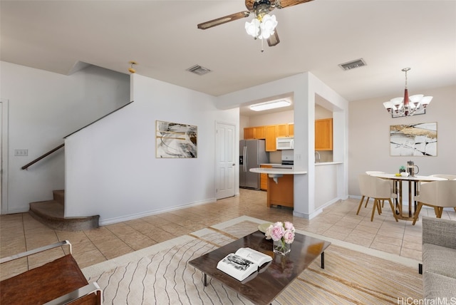 tiled living room with ceiling fan with notable chandelier