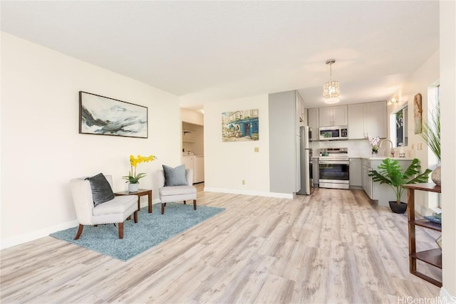 living area featuring sink, light hardwood / wood-style flooring, and washing machine and dryer