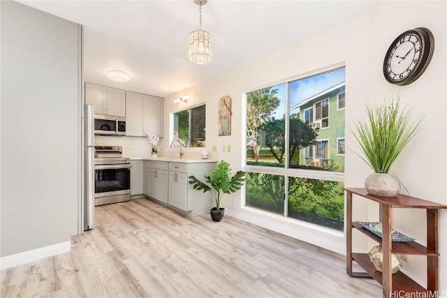 kitchen with light wood-type flooring, tasteful backsplash, hanging light fixtures, and stainless steel appliances