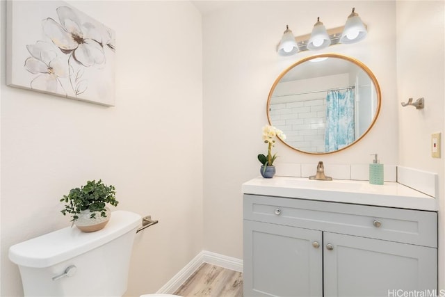 bathroom featuring hardwood / wood-style flooring, toilet, vanity, and walk in shower