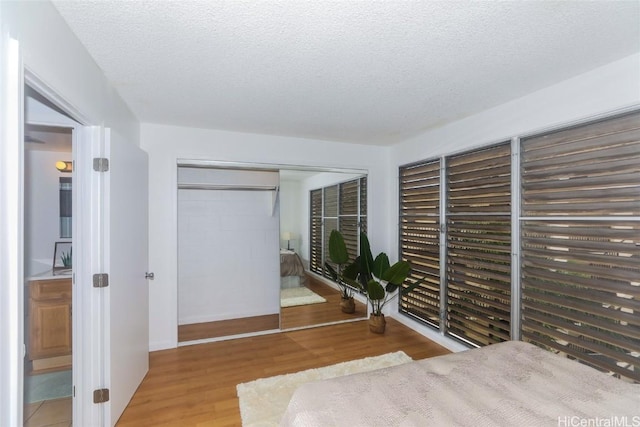 unfurnished bedroom featuring a textured ceiling, a closet, connected bathroom, and light hardwood / wood-style flooring