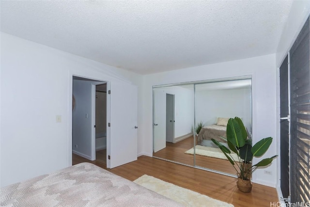 bedroom featuring light wood-type flooring, a closet, and a textured ceiling