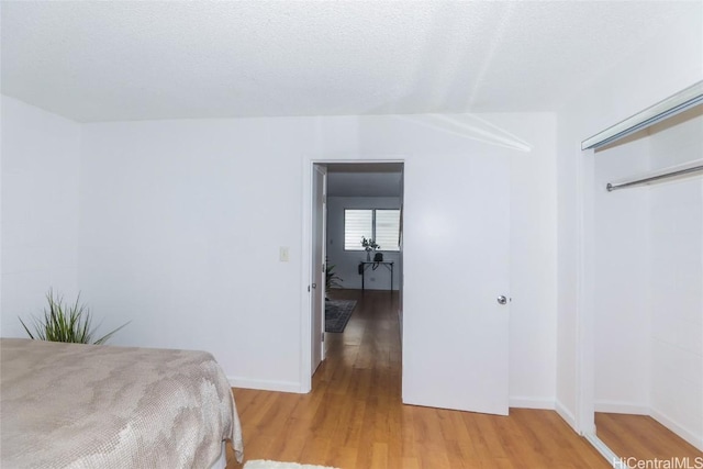 bedroom featuring light wood-type flooring, a closet, and a textured ceiling