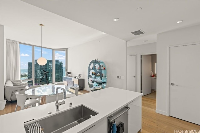 kitchen featuring light wood finished floors, visible vents, light countertops, pendant lighting, and a sink