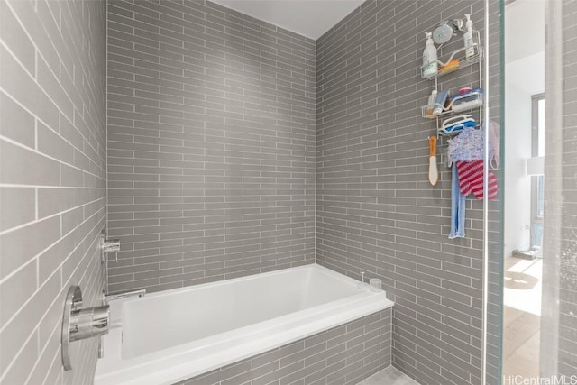 bathroom featuring tile walls, a washtub, and tiled shower