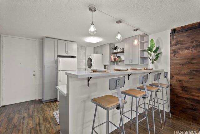 kitchen featuring pendant lighting, refrigerator, white fridge, kitchen peninsula, and a barn door