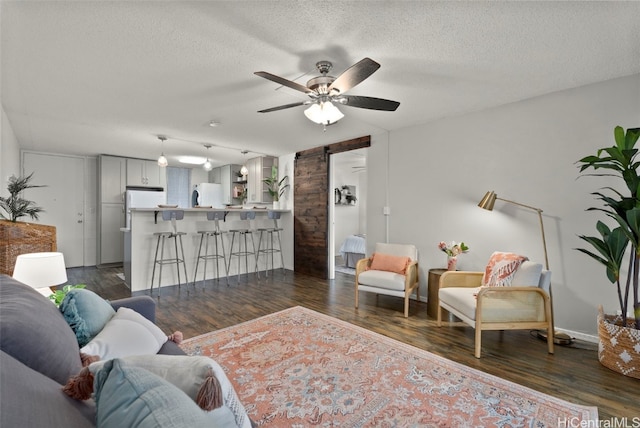 living room featuring a barn door, dark hardwood / wood-style floors, and a textured ceiling